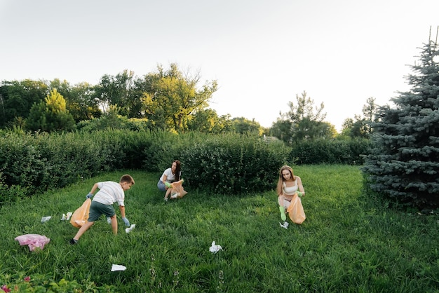 A group of adults and children together at sunset is engaged in garbage collection in the park Environmental care waste recycling Sorting garbage