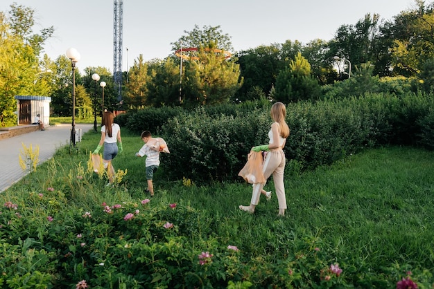 A group of adults and children together at sunset is engaged in garbage collection in the park Environmental care waste recycling Sorting garbage