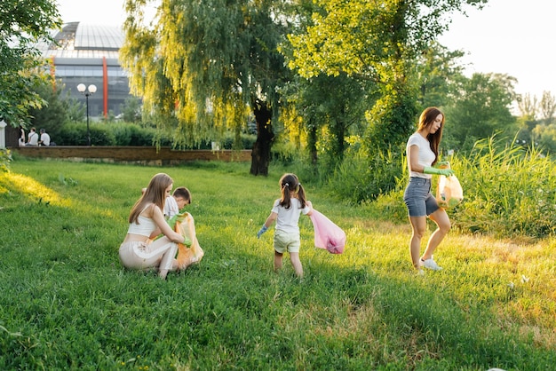 A group of adults and children together at sunset is engaged in garbage collection in the park Environmental care waste recycling Sorting garbage