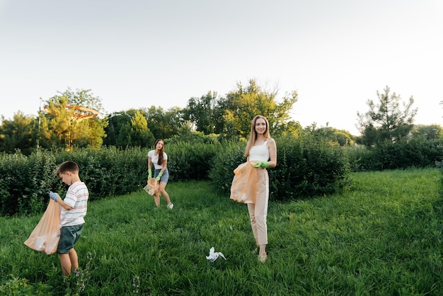 A group of adults and children together at sunset is engaged in garbage collection in the park Environmental care waste recycling Sorting garbage