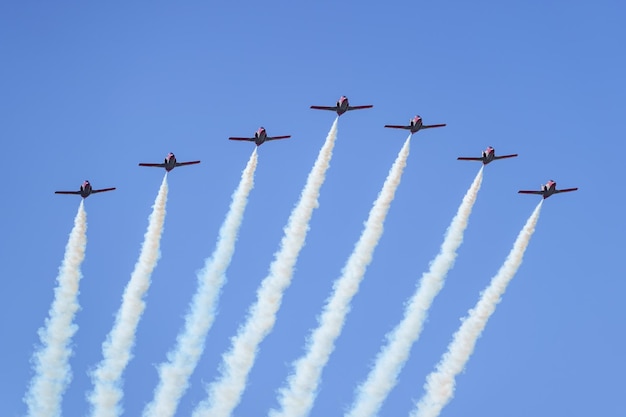 Group of aerobatics flying in formation close together and forming jets of clouds in the sky