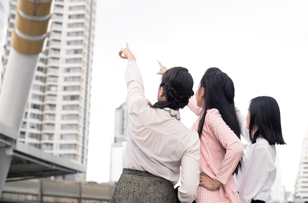 Group of asian businesswomen pointing forward with a smile in the concept of work progress at outdoorThai women office worker group.