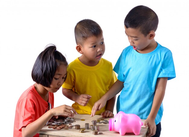 Group of asian children are helping putting coins into piggy bank isolated on white