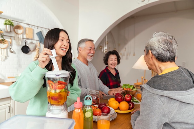 Group of asian elder senior friends at dinner party at home senior friend preparing salad and fruit juice with her daughter with smiling cheerful moment conversation with elder friend laugh smile