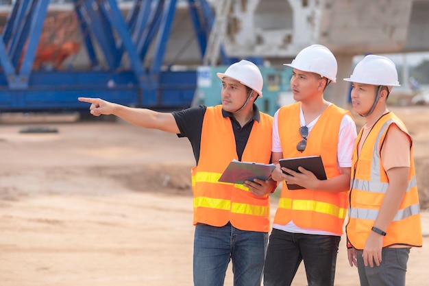 Group of asian engineers discuss about work at site of building under constructionThe contractor team discusses the design of the structureThree workers are working outside