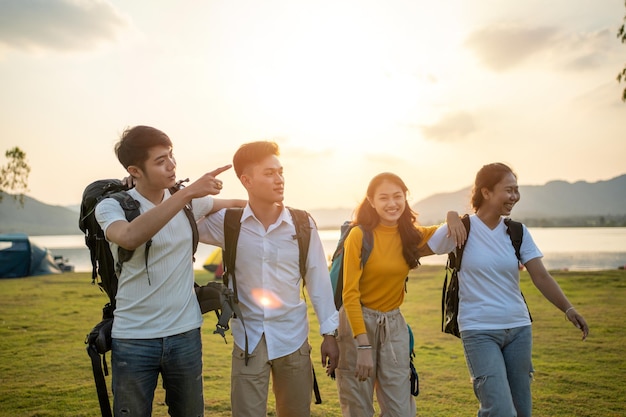 A group of Asian friends backpacking bag and walking for picnic and camping near lake