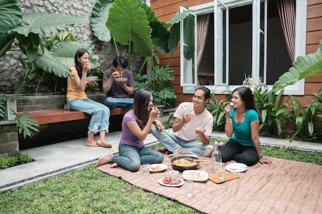 Photo group of asian friends having fun while eating and drinking in the backyard