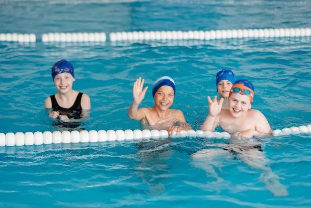 A group of boys and girls play and learn to swim in a modern swimming pool Development of children's sports Healthy parenting and promotion of children's sports