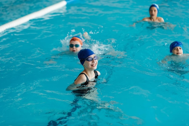 A group of boys and girls play and learn to swim in a modern swimming pool Development of children's sports Healthy parenting and promotion of children's sports