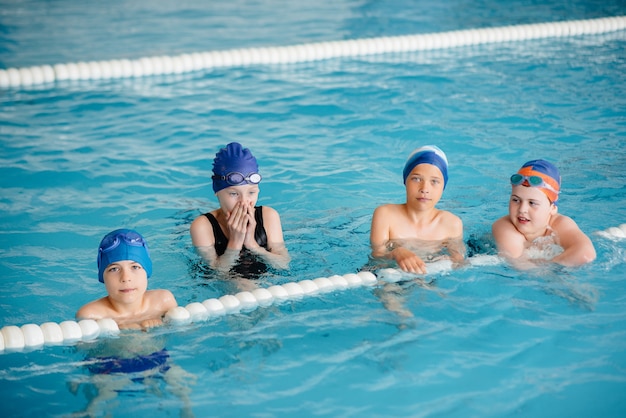 A group of boys and girls train and learn to swim in the pool with an instructor. Development of children's sports.