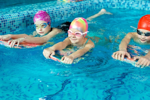 Group of boys and girls train and learn to swim in the pool with an instructor