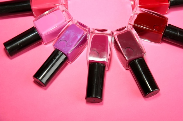 Group of bright nail polishes on pink background