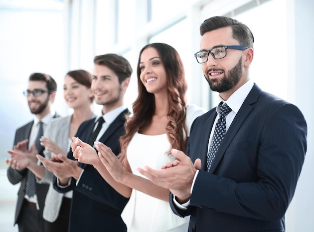 Group of business people applauding someone standing in the officeconcept of success