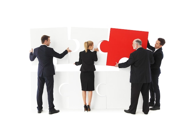 Group of business people assembling jigsaw puzzle isolated on white background