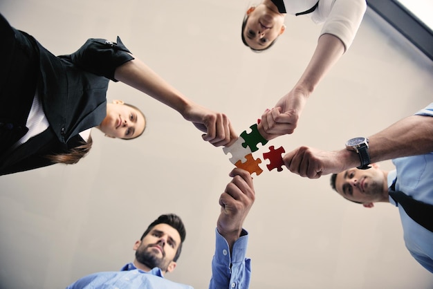 Group of business people assembling jigsaw puzzle and represent team support and help concept