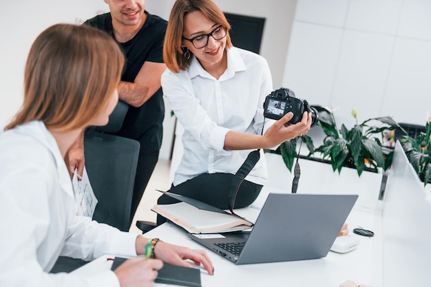 Group of business people in formal clothes indoors in the office looking at photos on the camera