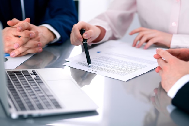 Group of business people and lawyers discussing contract papers sitting at the table, close up