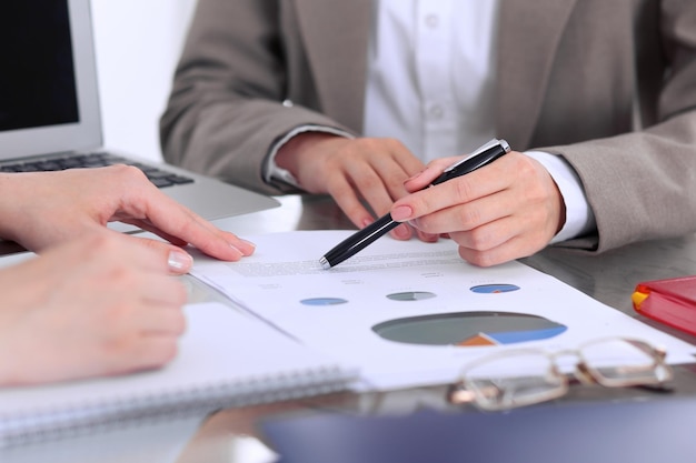 Group of business people at meeting  discussing financial results. Women pointing into laptop computer monitor