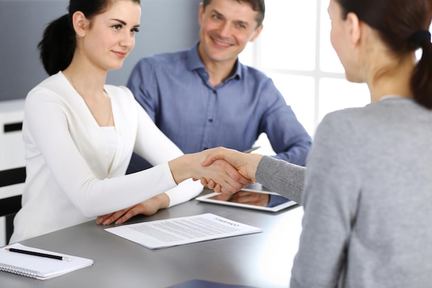 Group of business people shaking hands after discussing questions and achieving agreement at meeting in modern office. Handshake close-up. Teamwork, partnership and business concept.