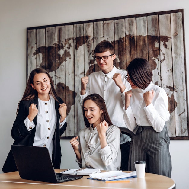 A group of business people working in an office at a joint meeting make a winning gesture