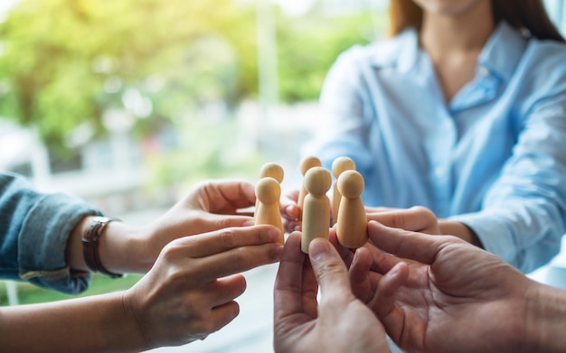 A group of business team holding and putting wooden people together in circle