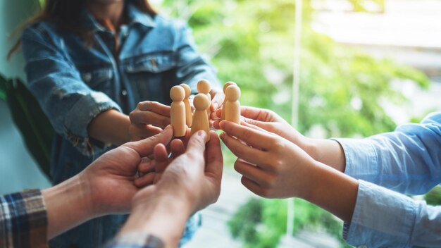 A group of business team holding and putting wooden people together in circle