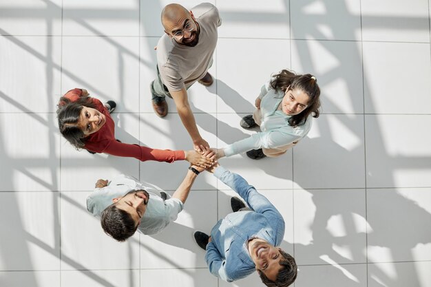 Photo group of business workers standing bumping fists at the office