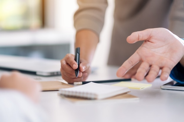 Group of businessman discussing and writing on notebook on the table in office