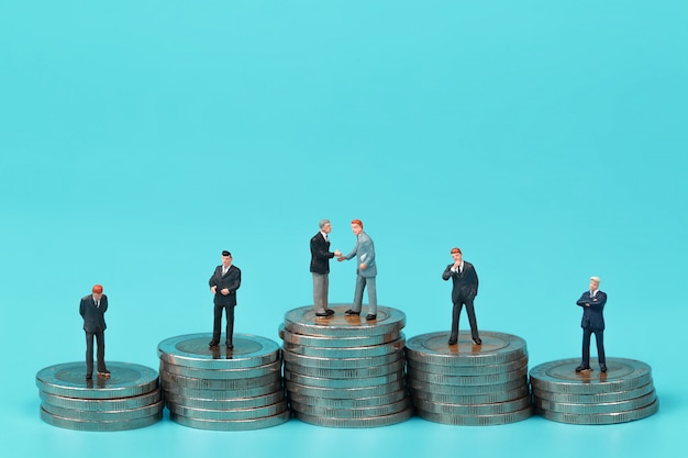 a group of businessman standing on coin stacking podium