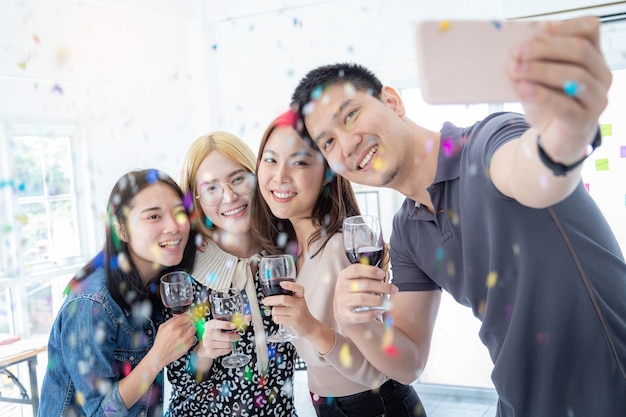 A group of businessmen holding wine glasses and taking a selfie at a successful business celebration.