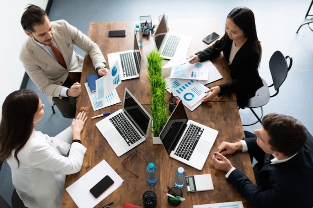 A group of businessmen at a large desktop discussing business negotiations top view