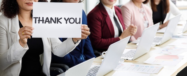 Photo group of businesswomen sitting at working desk, clapping hands and show thank you word for appreciating to someone in modern office company. concept of good circumstance in company with colleagues.