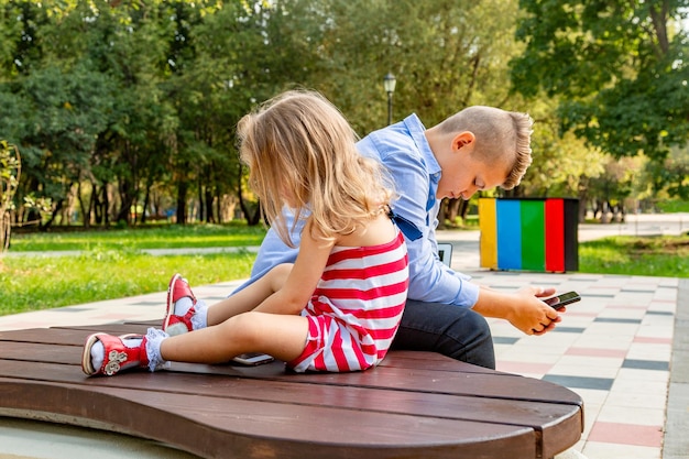 Group of busy kids looking at their phones texting sms and playing sitting outside