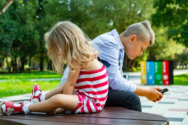 Group of busy kids looking at their phones texting sms and playing sitting outside