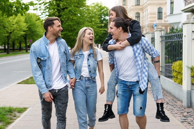 Group of cheerful best friends are having fun while walking by city street