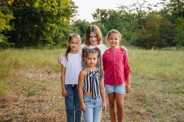 A group of cheerful girls are smiling and playing in the Park during sunset. Children's summer camp.