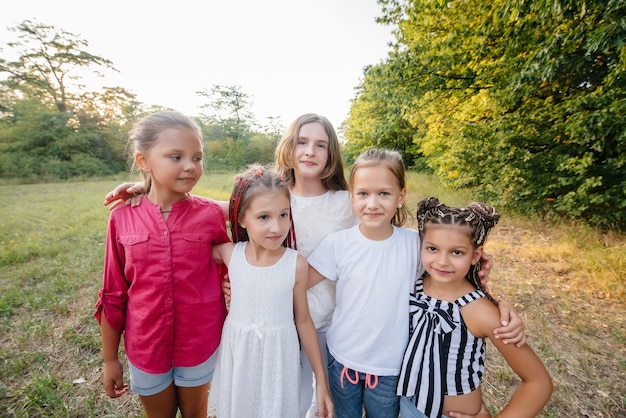 A group of cheerful girls are smiling and playing in the Park during sunset. Children's summer camp.