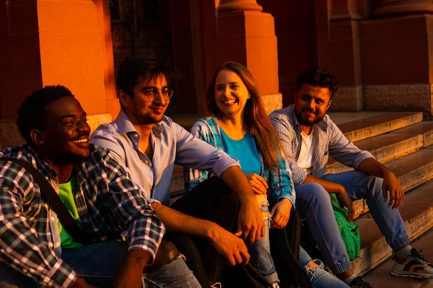 The group of cheerful high school students are sitting in the city