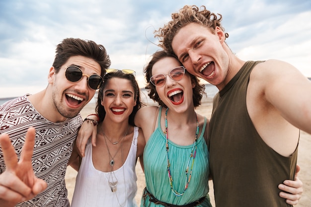 Group of a cheerful young friends walking at the beach, laughing