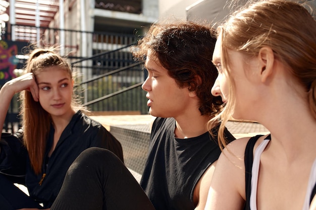 A group of cheerful young people girls and guys are discussing and debating while playing basketball on a street playground Diversity men and women play basketball together