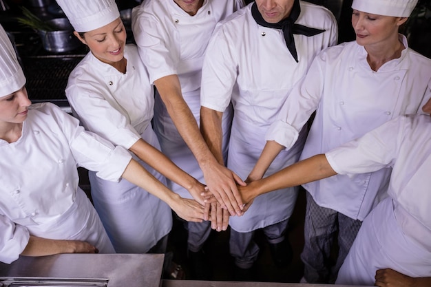 Photo group of chefs formig hands stack in kitchen