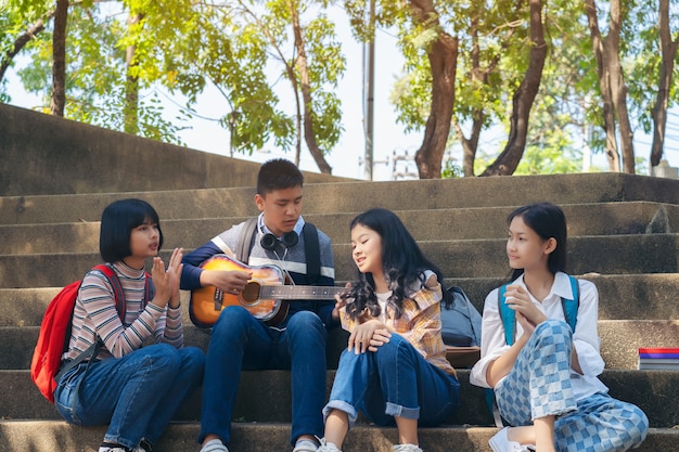 Group of child student playing guitar and singing songs together in summer park	