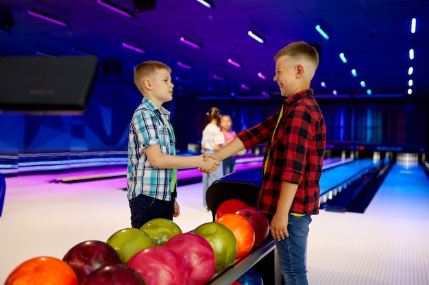 Photo group of children in bowling alley. kids are preparing to score a strike. boys and girls having fun in entertainment center together, little bowlers