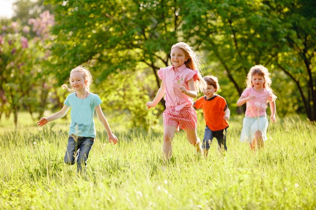 A group of children playing and running in the park on a green gozon.