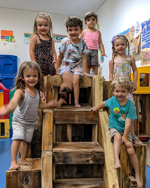 Photo a group of children sit on a wooden platform with a sign that says  the word  on it