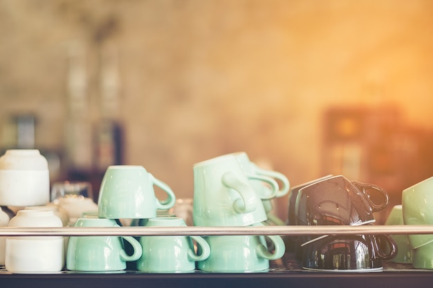 Group of coffee cups in cafe bar, green brown and white coffee mug glass on shelf in shop