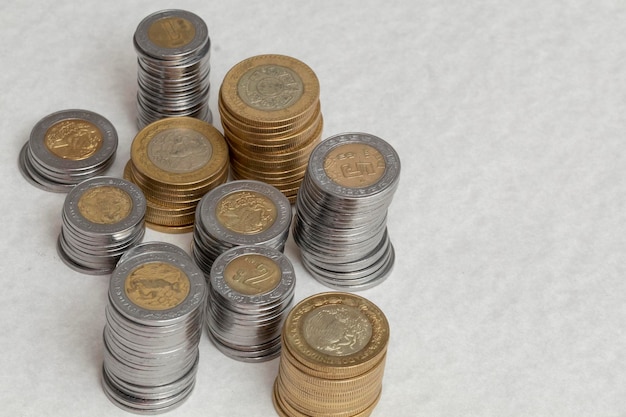 Group of coins stacked on the corner of a table with copy space Mexican pesos