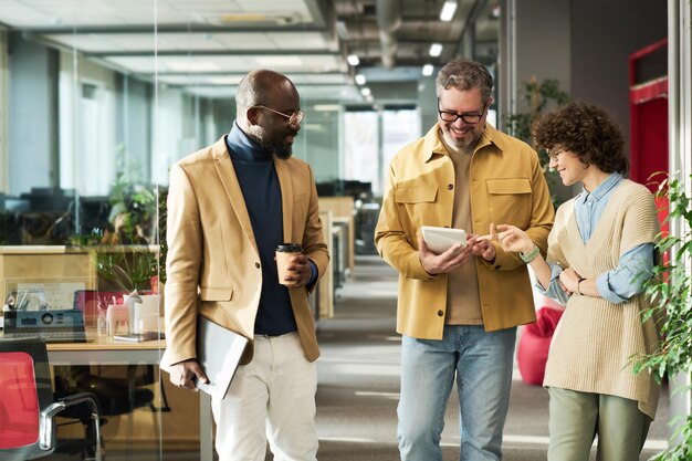 Group of colleagues discussing online data or video on tablet screen