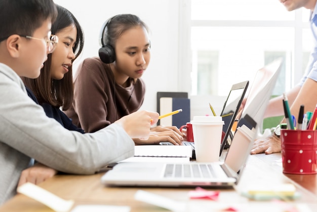 Group of college Asian students looking at laptop computer discussing project