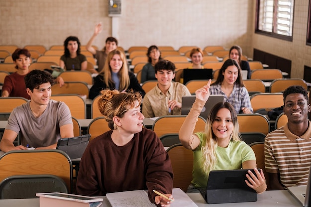 Group of college students raising their hands to ask the teacher during class